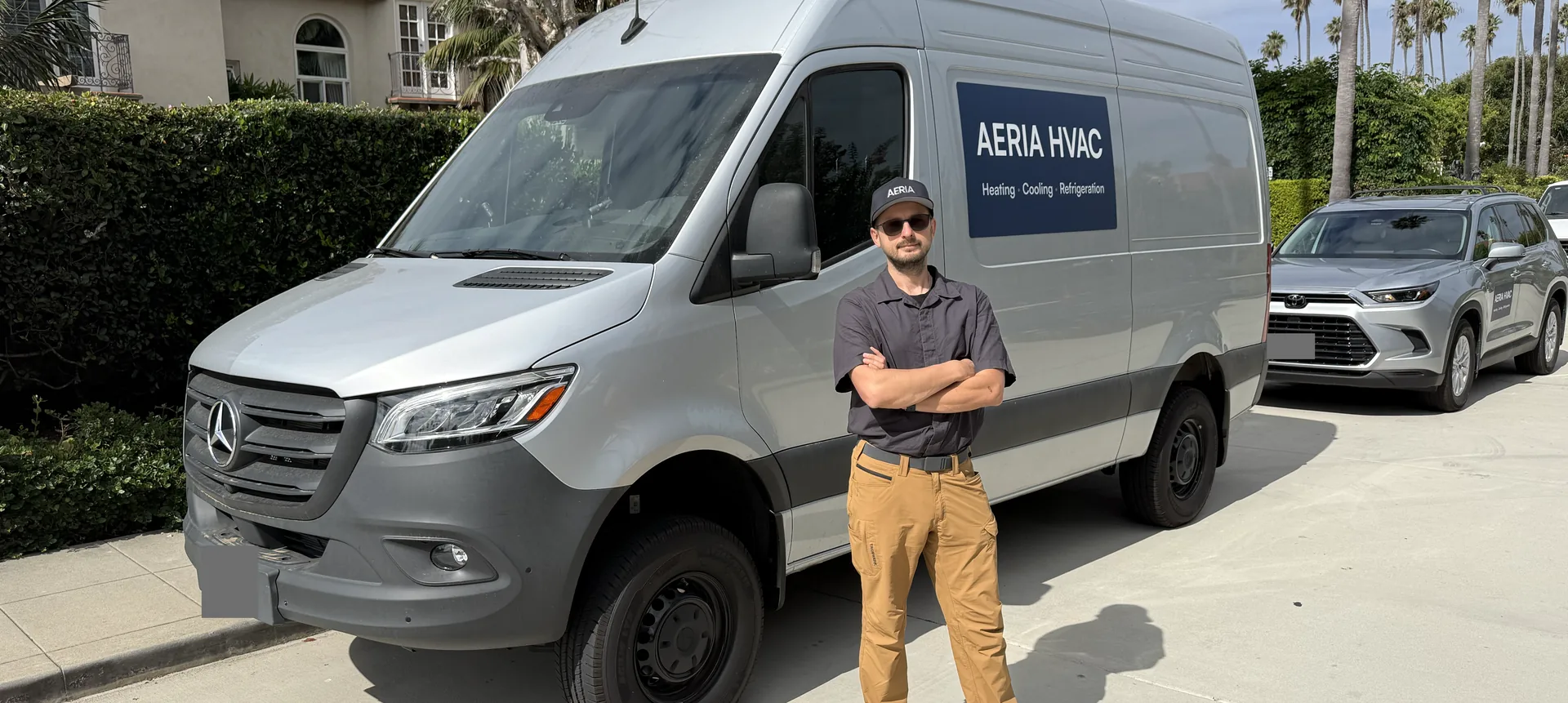 AERIA HVAC service van with a team member standing in front of it on a residential street